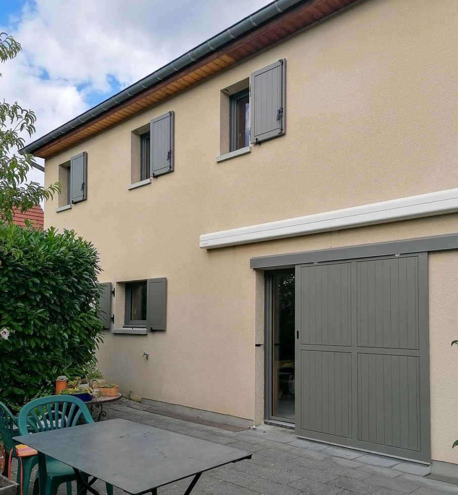 Pose fenetres double vitrage bois-alu à AVANNE dans le Doubs Pose fenêtres double vitrage bois-alu à AVANNE dans le Doubs - Façade de la maison avec vue sur un volet roulant pour une porte-fenêtre